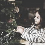 little girl putting decorations on tree