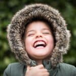 Boy laughing with hood up on his coat